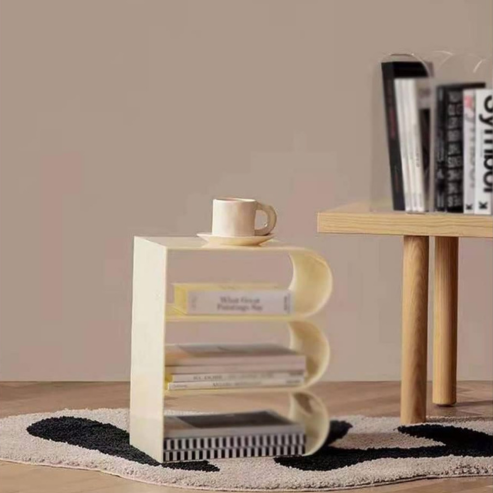 Étagère crème incurvée avec livres et tasse, à côté d’un bureau.