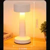 Lampe de table blanche allumée, projetant une lumière chaude.