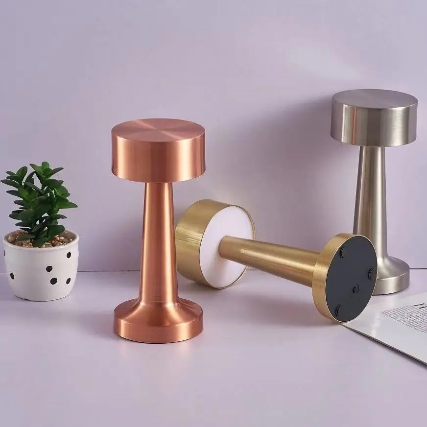Lampes de table aux finitions cuivrées, dorées et argentées, dont une couchée.
