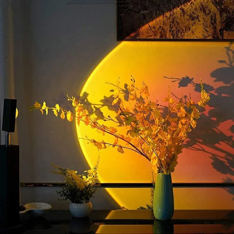 Halo jaune et orange projeté derrière un vase avec des branches fleuries.